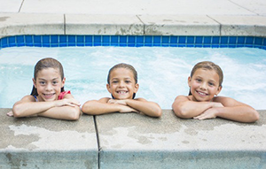 Three smiling children in pool