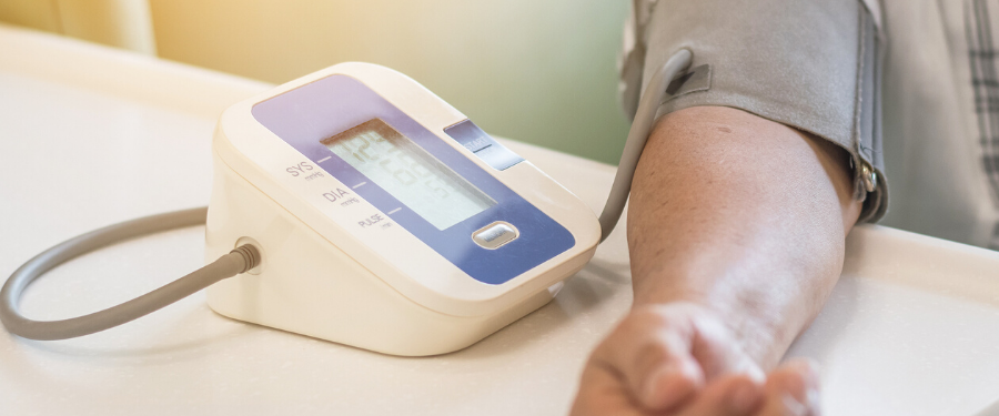 A man's arm in a blood pressure self-monitor machine