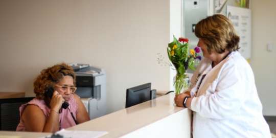 nurse talking to a woman at a front desk