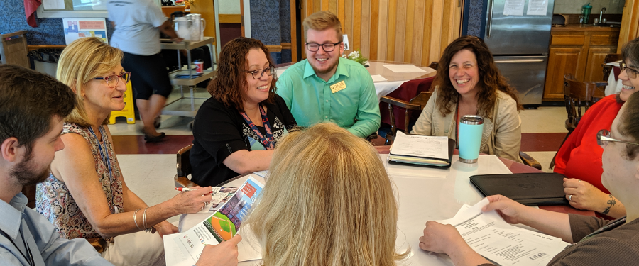 A group of people representing different local agencies sit around a table and work toward a common goal.