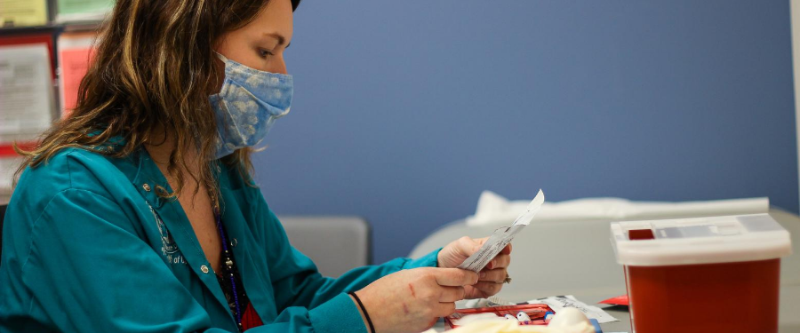A masked LCPH staff member prepares an HIV test