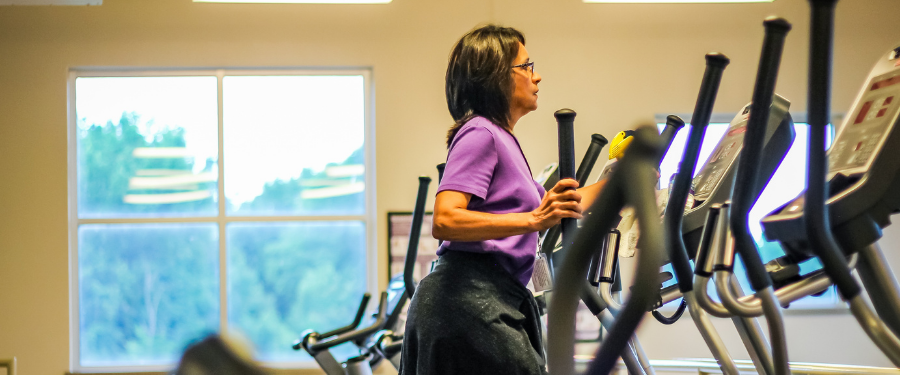 A female in a purple shirt using fitness equipment. 