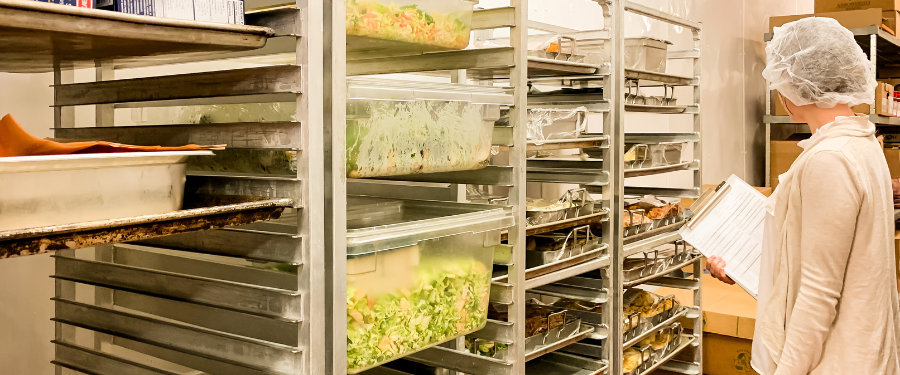 An LCPH health inspector reviews stacked storage of salads and breads.