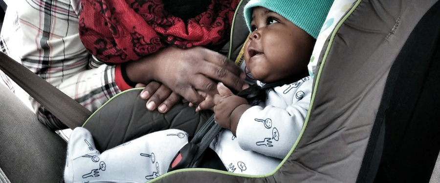 A baby gets tucked safely into its car seat.