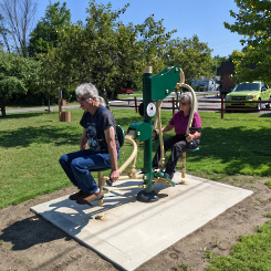 A woman and man working out on outdoor fitness equipment