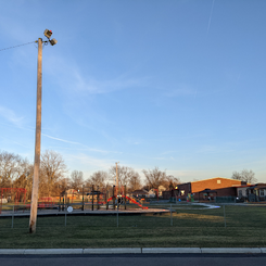 a big light fixture shining on a playground & trail