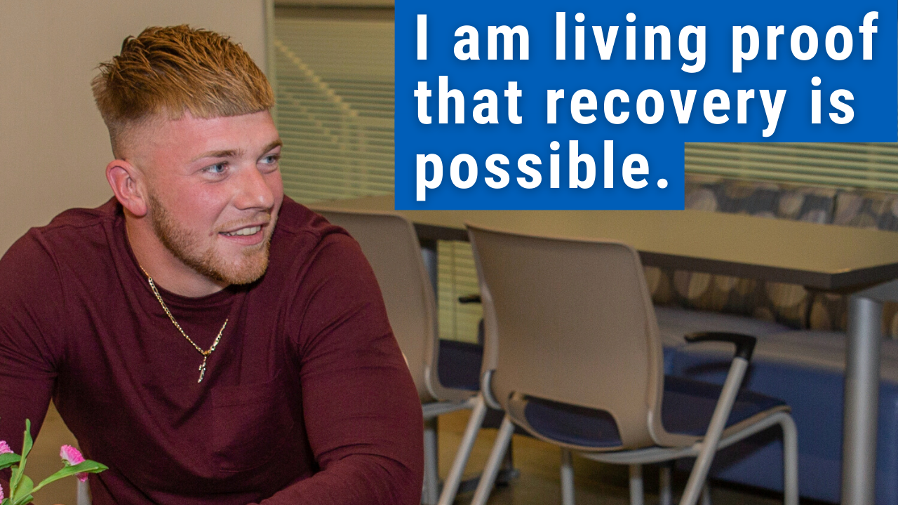 man sitting at table smiling with text "I am living proof recovery is possible" 