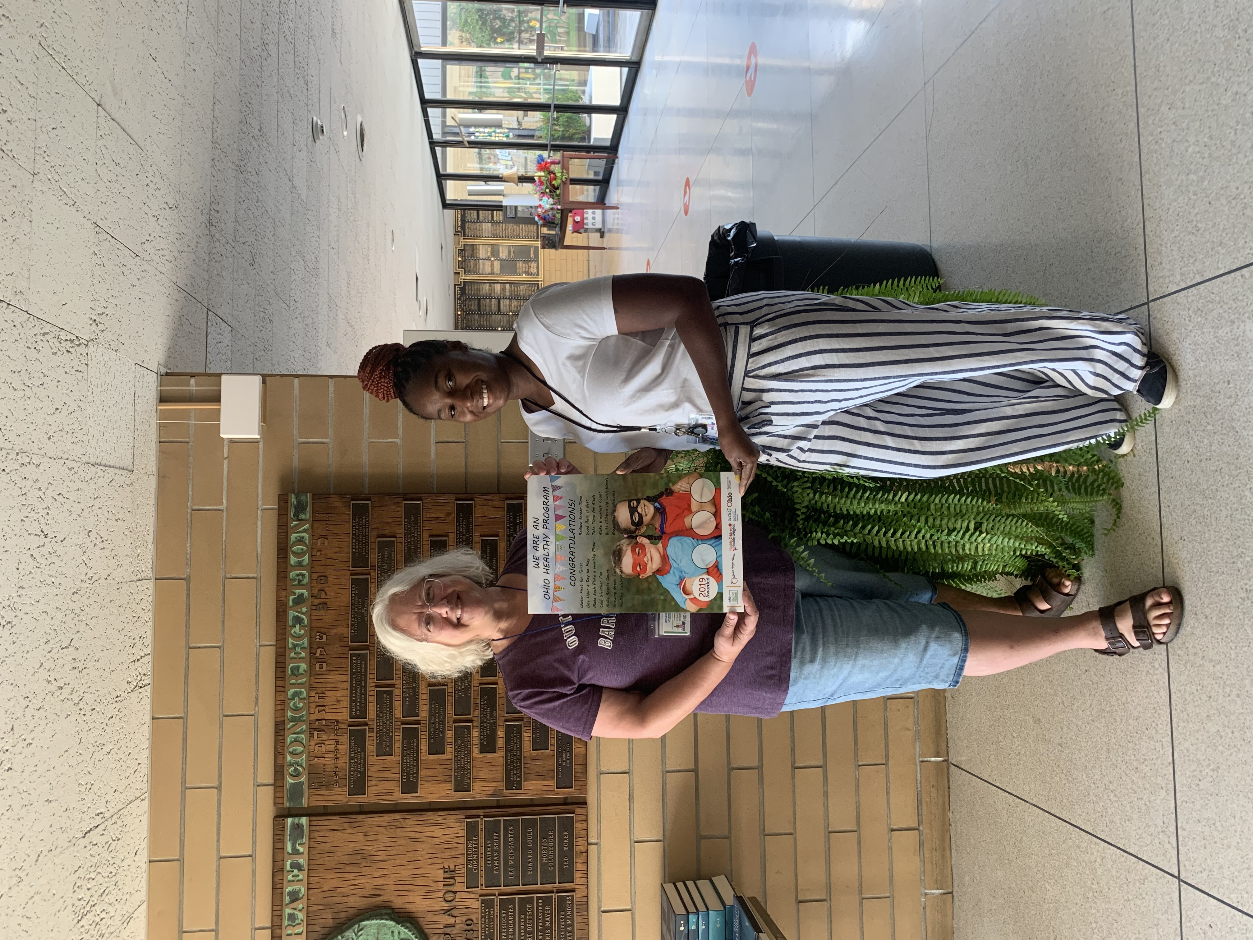 Two women standing with an ohio healthy programs poster 